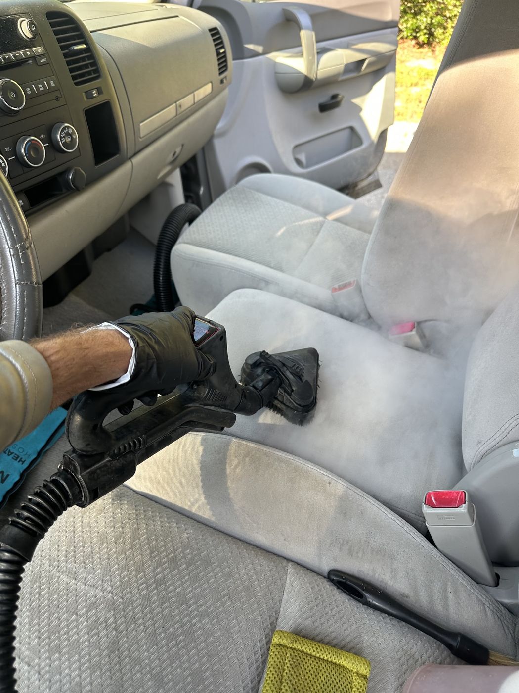Steam cleaning a cloth front seat during interior car detailing