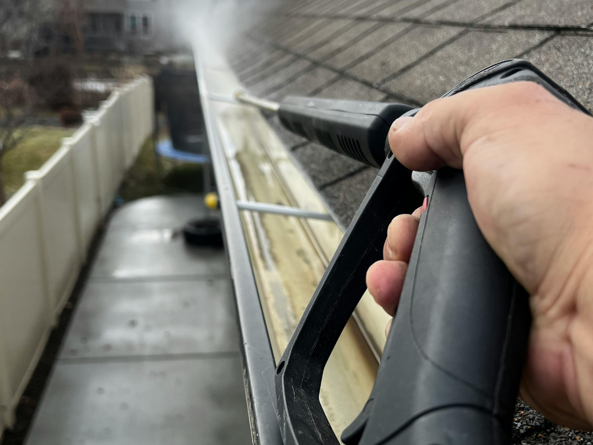 Gutter being flushed clean with a pressure washer wand in Fort Walton Beach